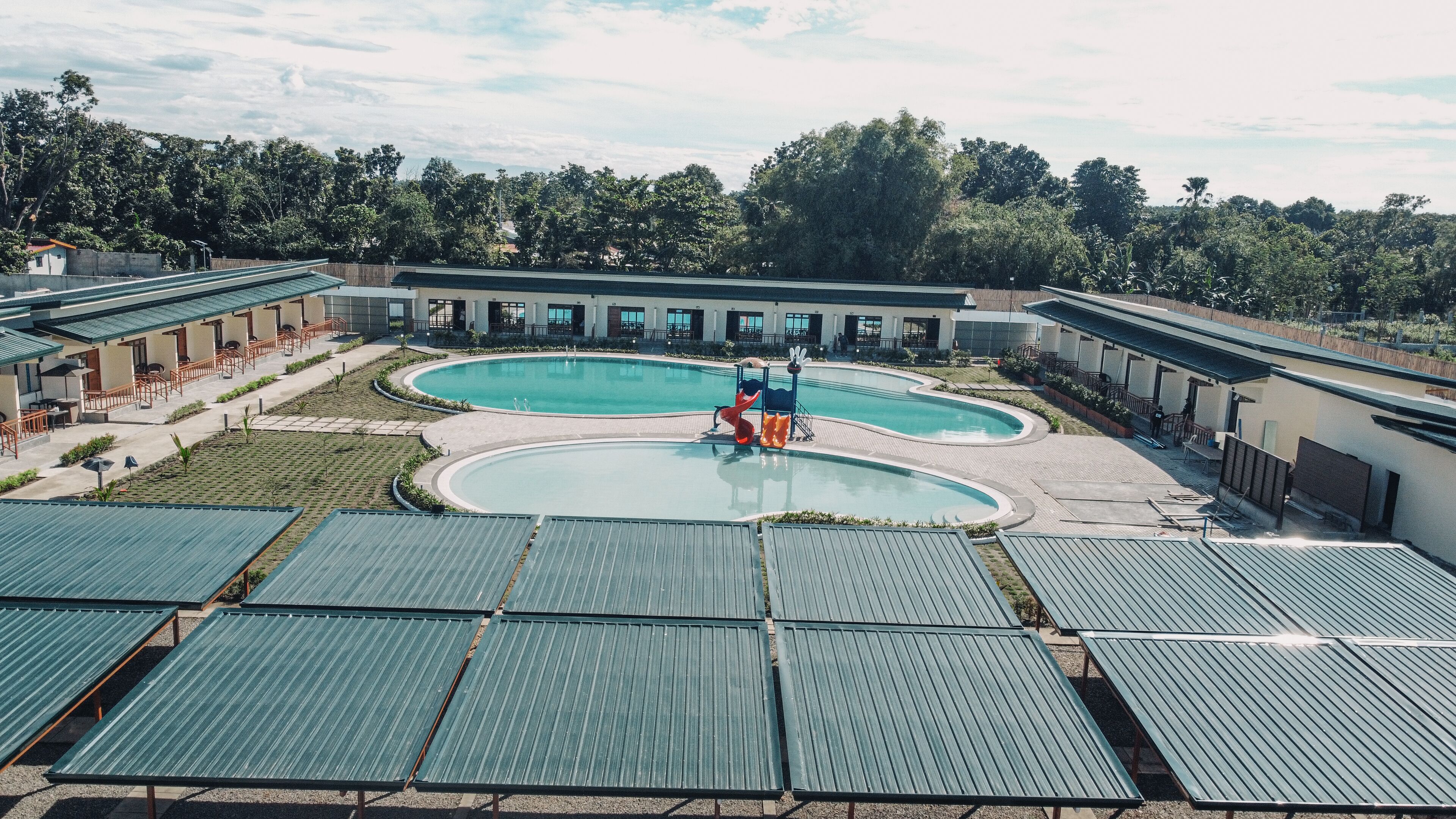 A resort with multiple swimming pools, a children's play area, and covered outdoor seating areas.
