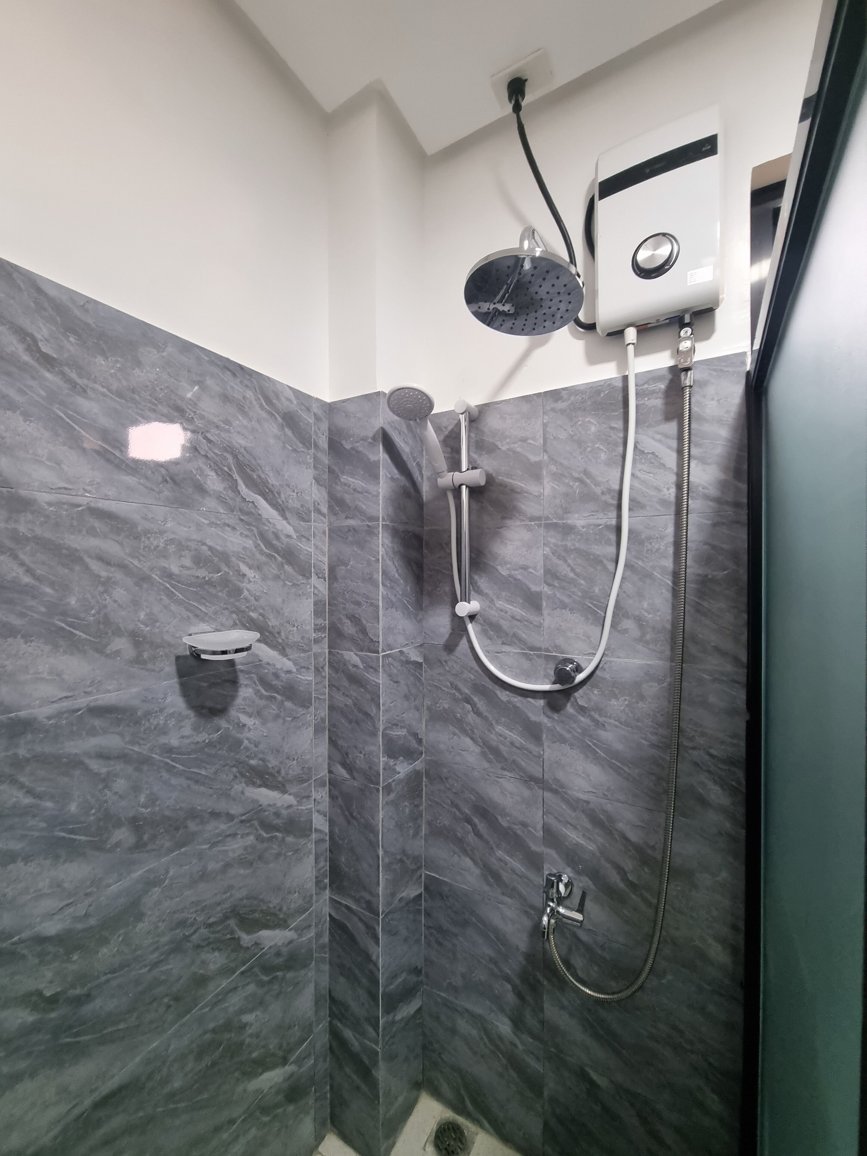 Una ducha moderna con cabezal de ducha manual, grifo empotrado y accesorio de ducha de mano.