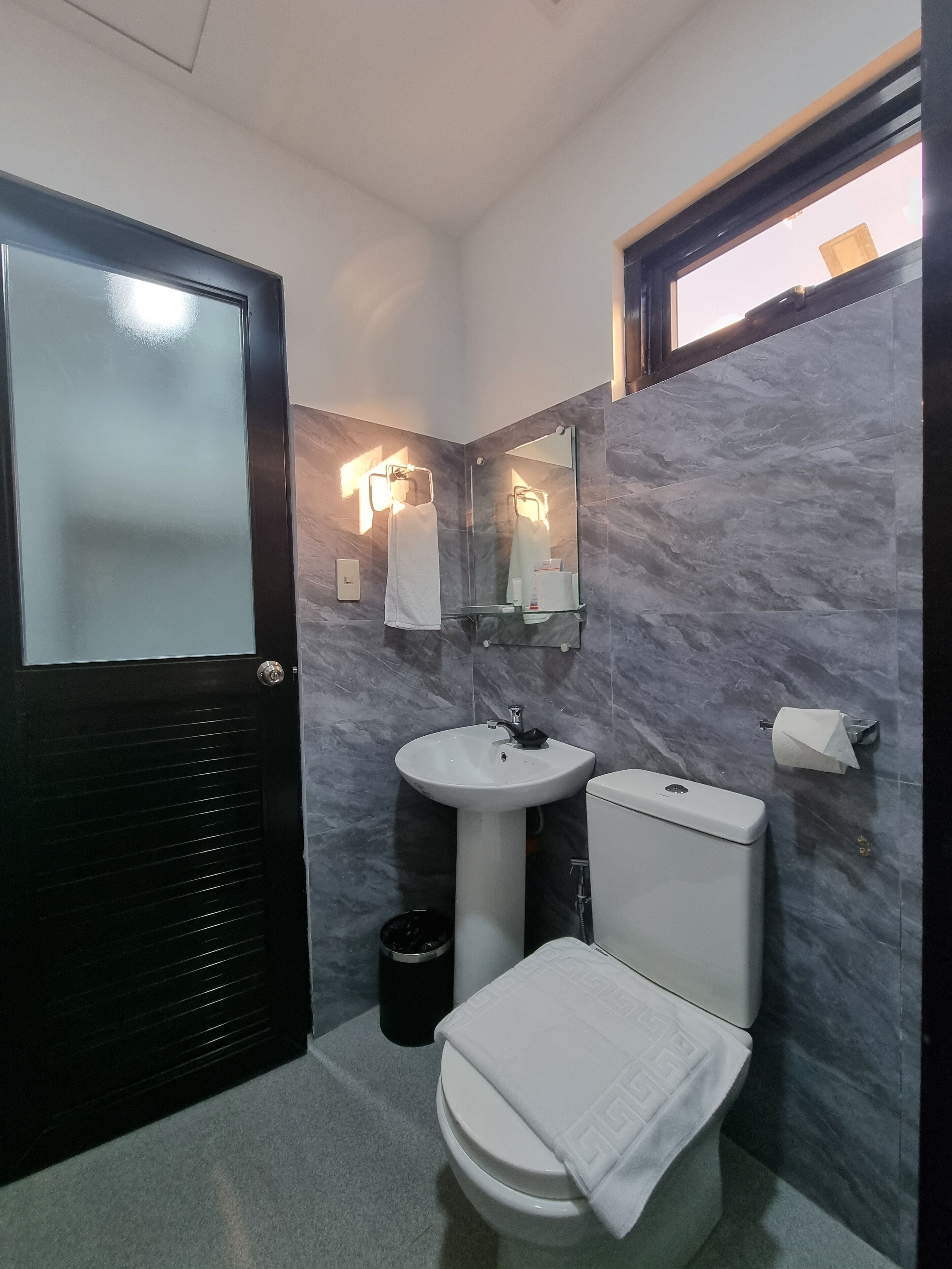 Un baño pequeño con inodoro, lavamanos y espejo.