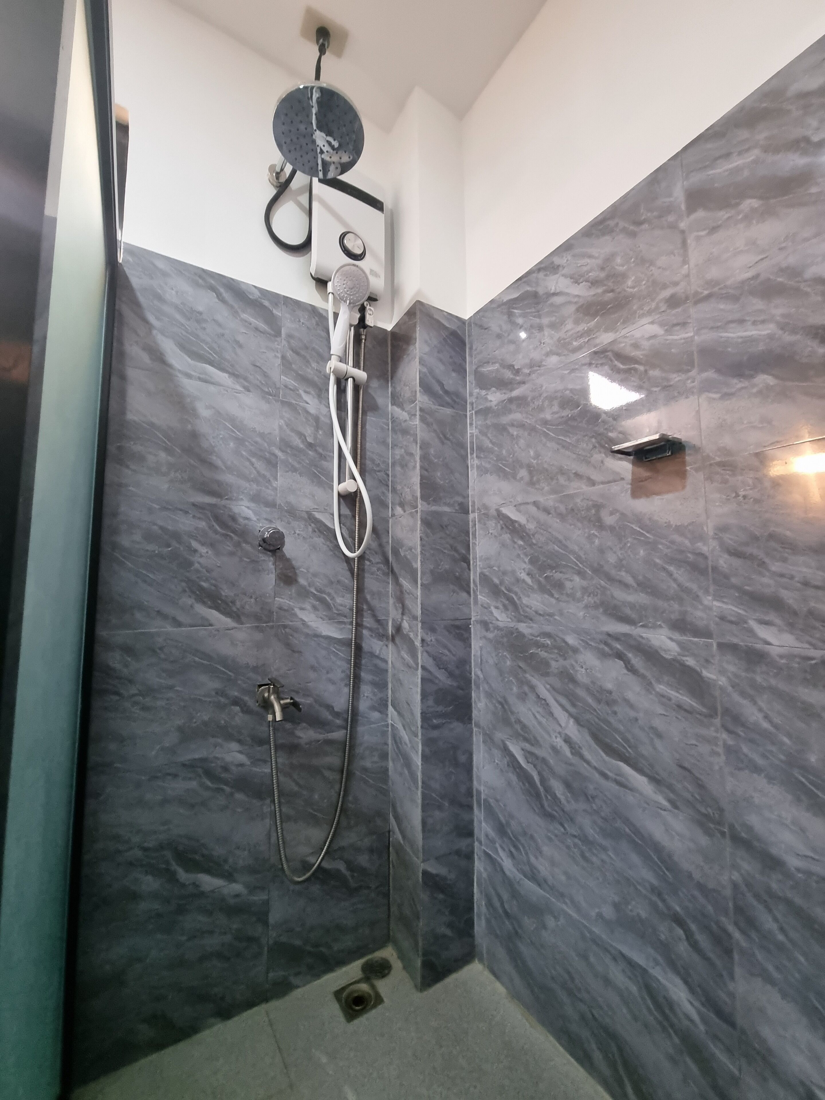 Een moderne badkamer met een inloopdouche, marmeren wanden en een zichtbare boiler.