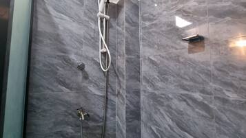 Een moderne badkamer met een inloopdouche, marmeren wanden en een zichtbare boiler.