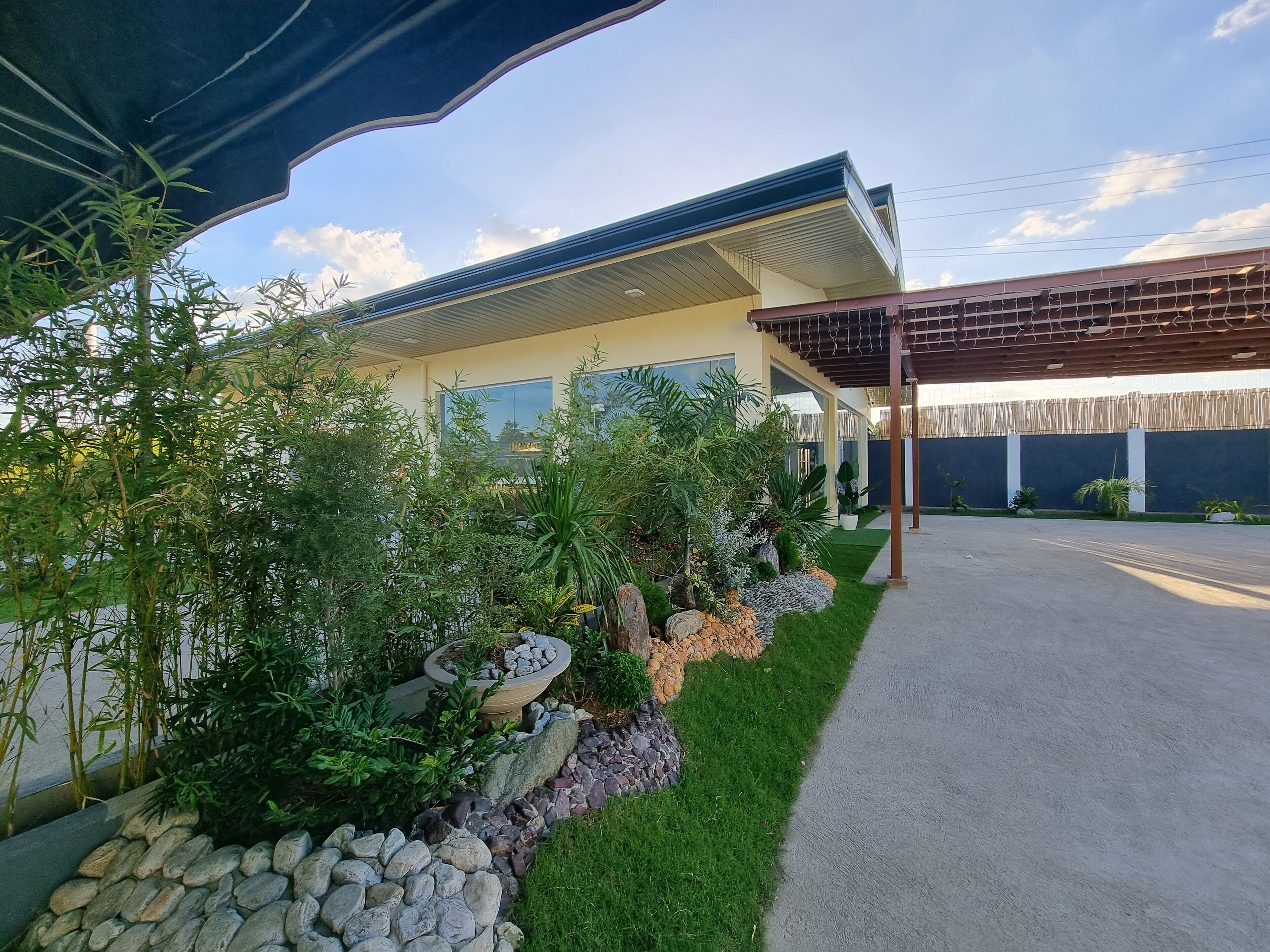 A modern house with a covered porch, a well-maintained garden, and a paved driveway.