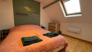 Een slaapkamer met een bed, een raam, een dressoir en een airconditioning.