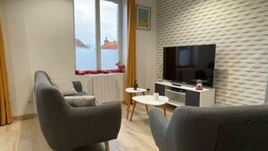 Een moderne woonkamer met een bank, een televisie en een klein tafeltje.