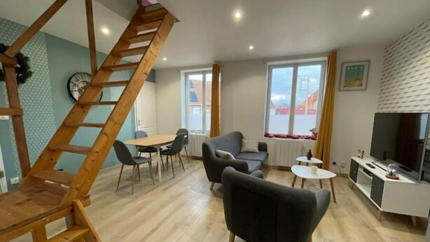 Een moderne woonkamer met een houten trap, een eethoek en een televisie.