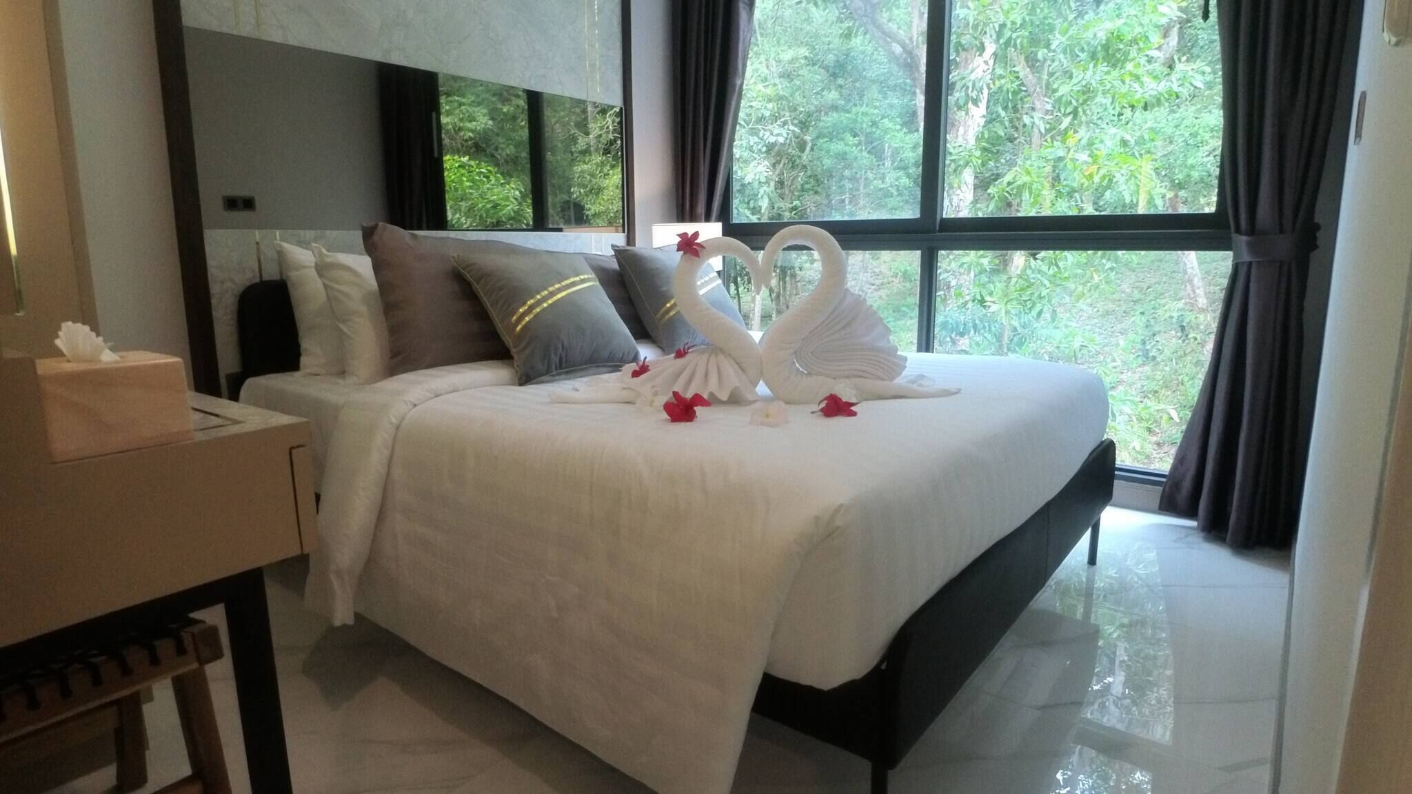 A neatly made bed with a white duvet, pillows, and decorative swan-shaped pillows.