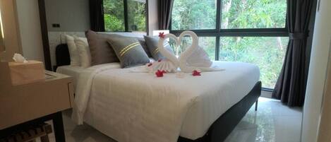 A neatly made bed with a white duvet, pillows, and decorative swan-shaped pillows.