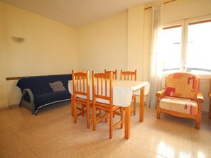 Ein Essbereich mit Tisch und Stühlen, einer Couch und einem Fenster mit Vorhängen.