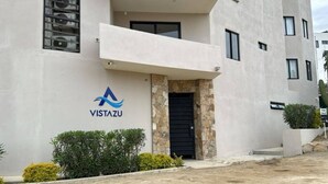 A modern building with a stone entrance, a logo for Vistazu, and a 'For Sale' sign.