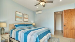 A bedroom with a bed, two bedside tables, a ceiling fan, and a door.
