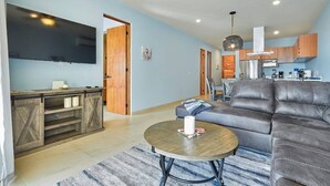 A modern living room with a leather sofa, a wooden coffee table, and a flat-screen TV mounted on the wall.