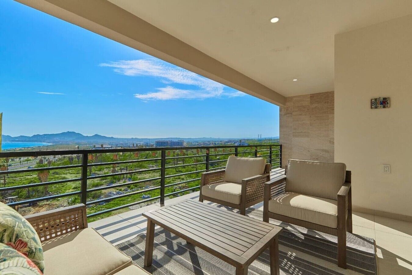 A balcony with a view of mountains and a cityscape, furnished with a table and two chairs.