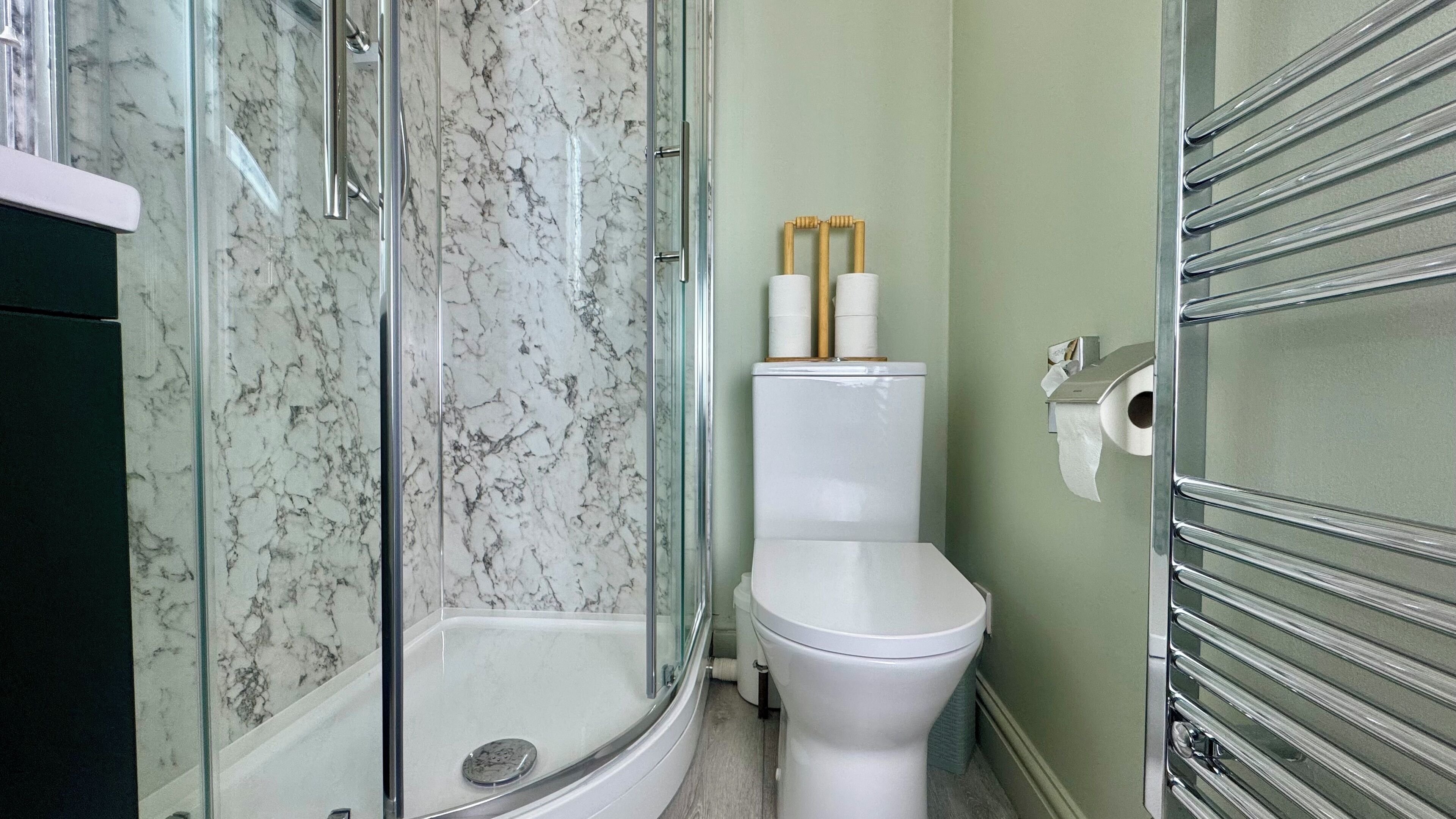 Un baño con cabina de ducha de vidrio, inodoro y dispensador de toallas de papel.