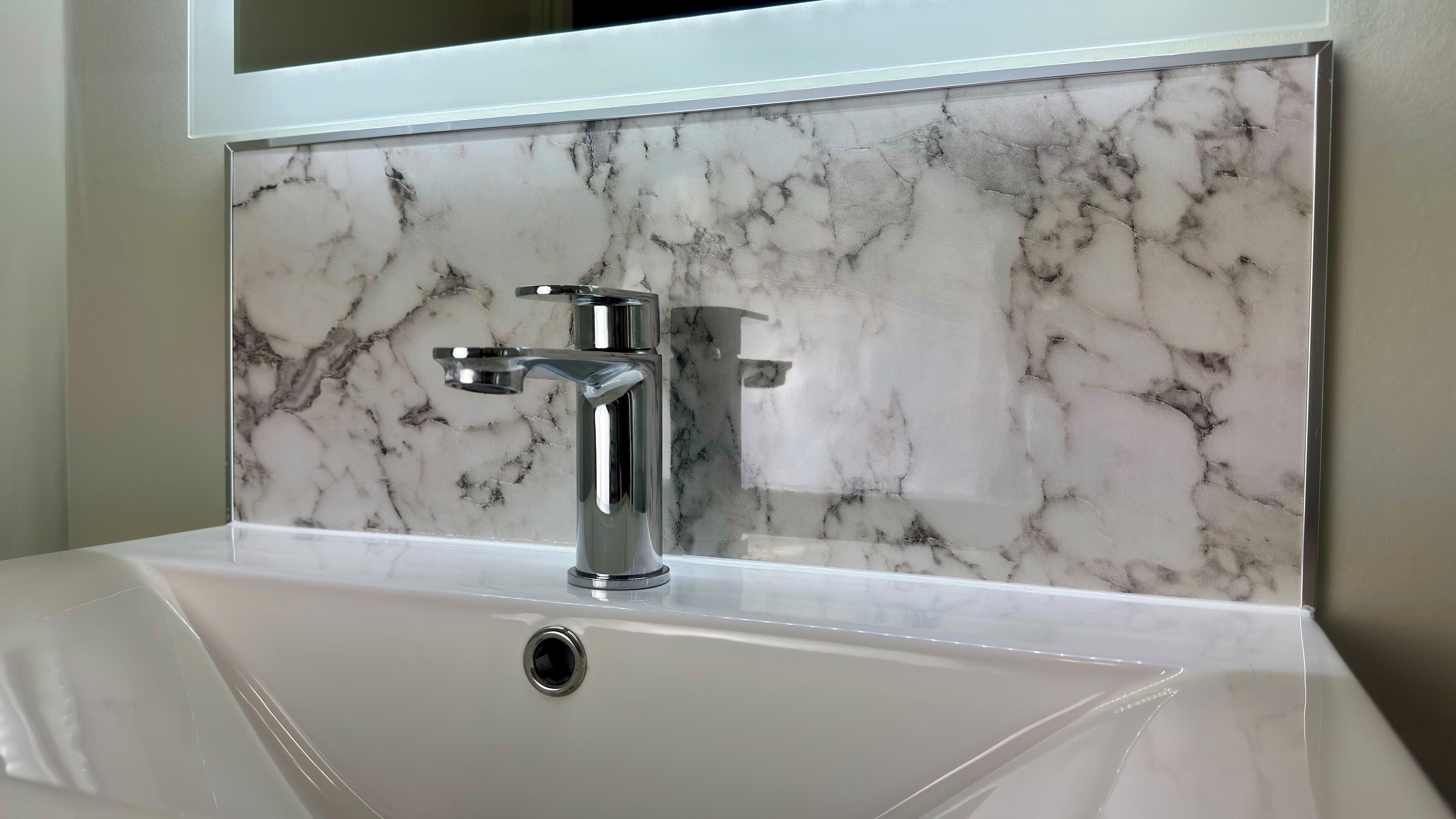 A bathroom sink with a modern faucet and a marble backsplash.