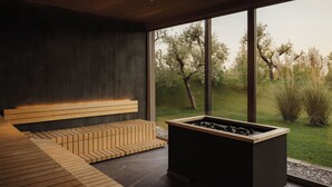 Un intérieur moderne avec un banc intégré, un foyer et de grandes fenêtres offrant une vue sur l’extérieur.