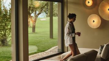 Una habitación con ventanas amplias, un sofá y luces fijadas a la pared.