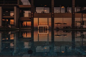 Un edificio moderno con un estanque reflectante, grandes ventanales y zonas de estar al aire libre.