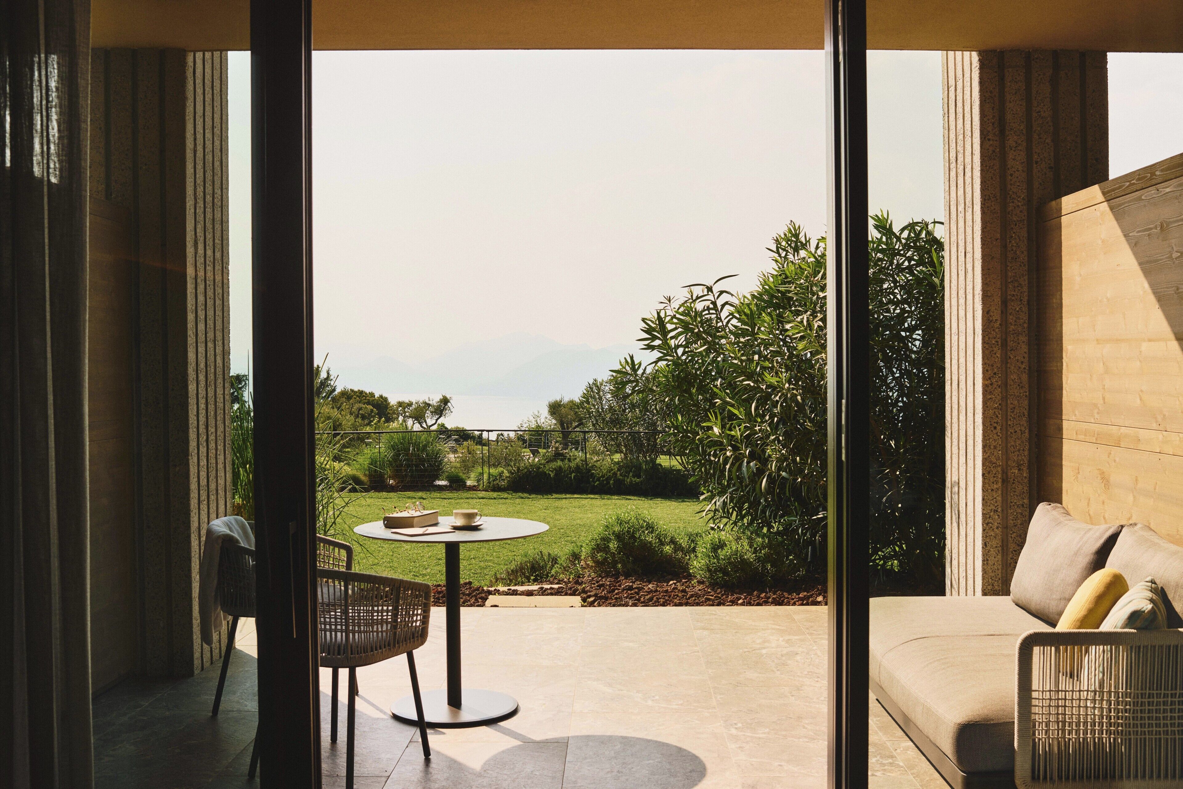 Un espace extérieur aménagé avec une table et des chaises, un canapé et une vue sur un jardin paysager.