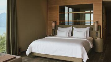 Una habitación de hotel moderna con una cama grande, cabecera de madera y vistas a las montañas.