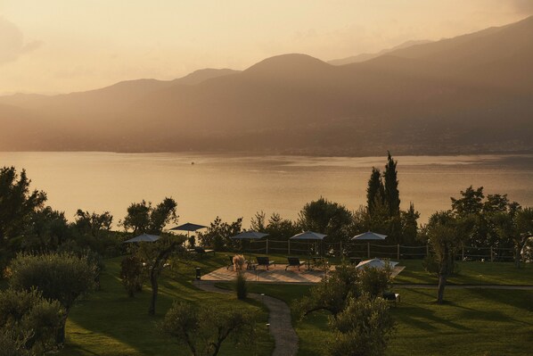 A lakeside resort with outdoor seating areas, a walking path, and a view of distant mountains. - Cape of Senses (Torri del Benaco)