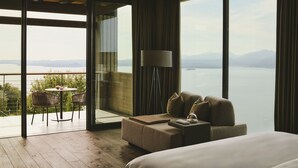 Une chambre d’hôtel avec une grande fenêtre, un canapé, une table avec des chaises et une lampe.