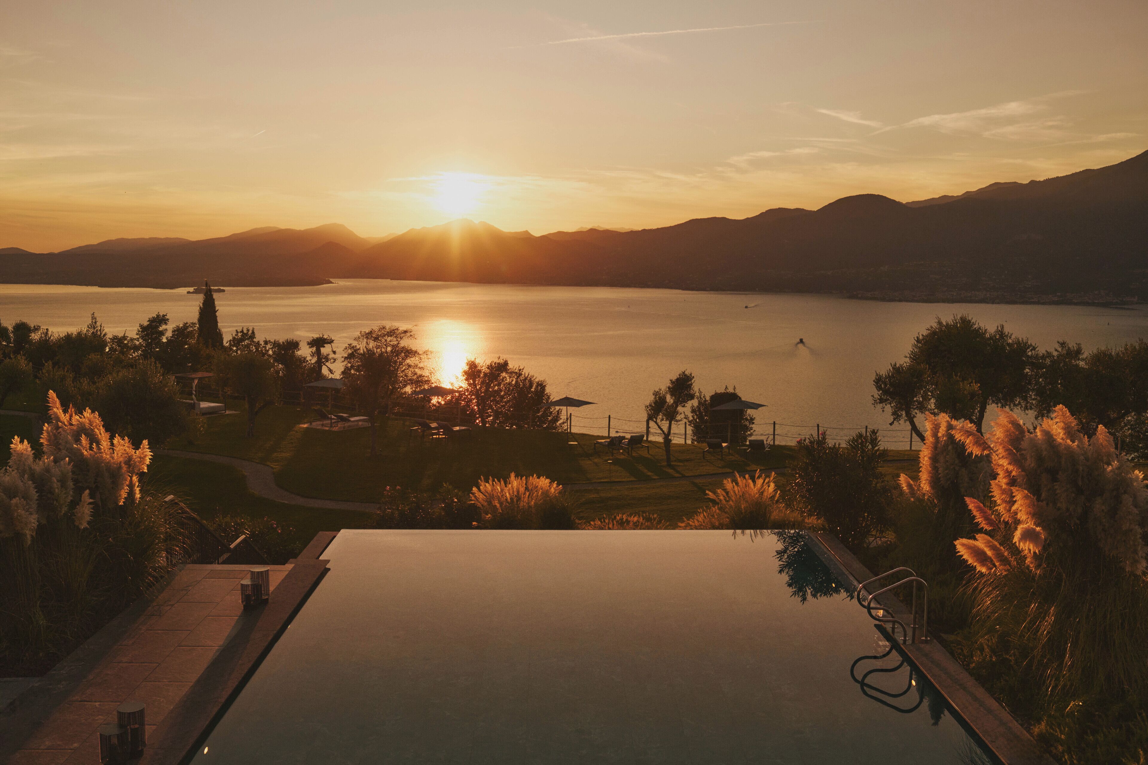 Una vista tranquila de un lago al atardecer, con una piscina y abundante vegetación.