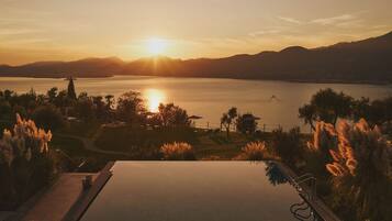 Una vista tranquila de un lago al atardecer, con una piscina y abundante vegetación.
