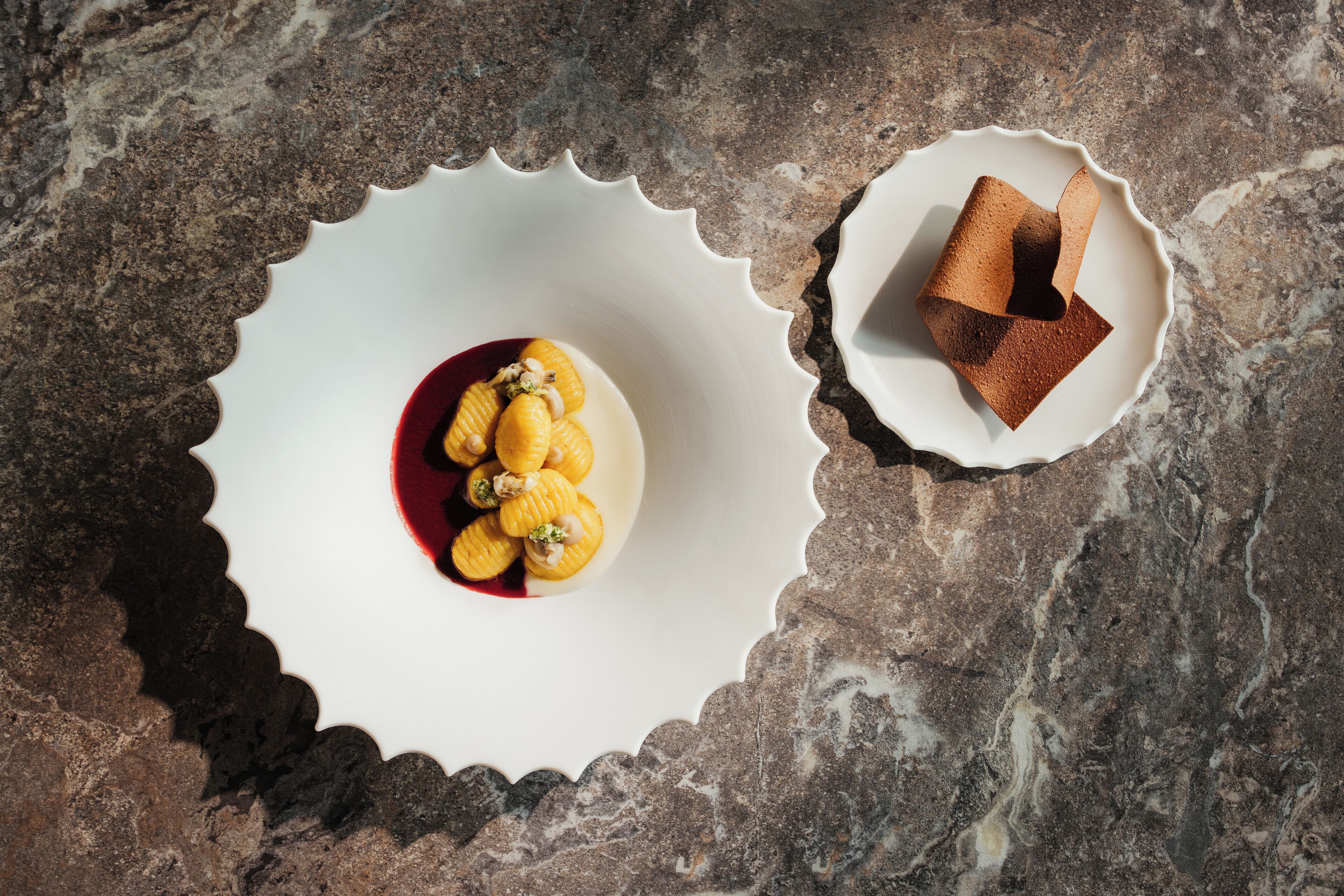 A dessert on a white plate with a scalloped edge, placed on a textured surface.