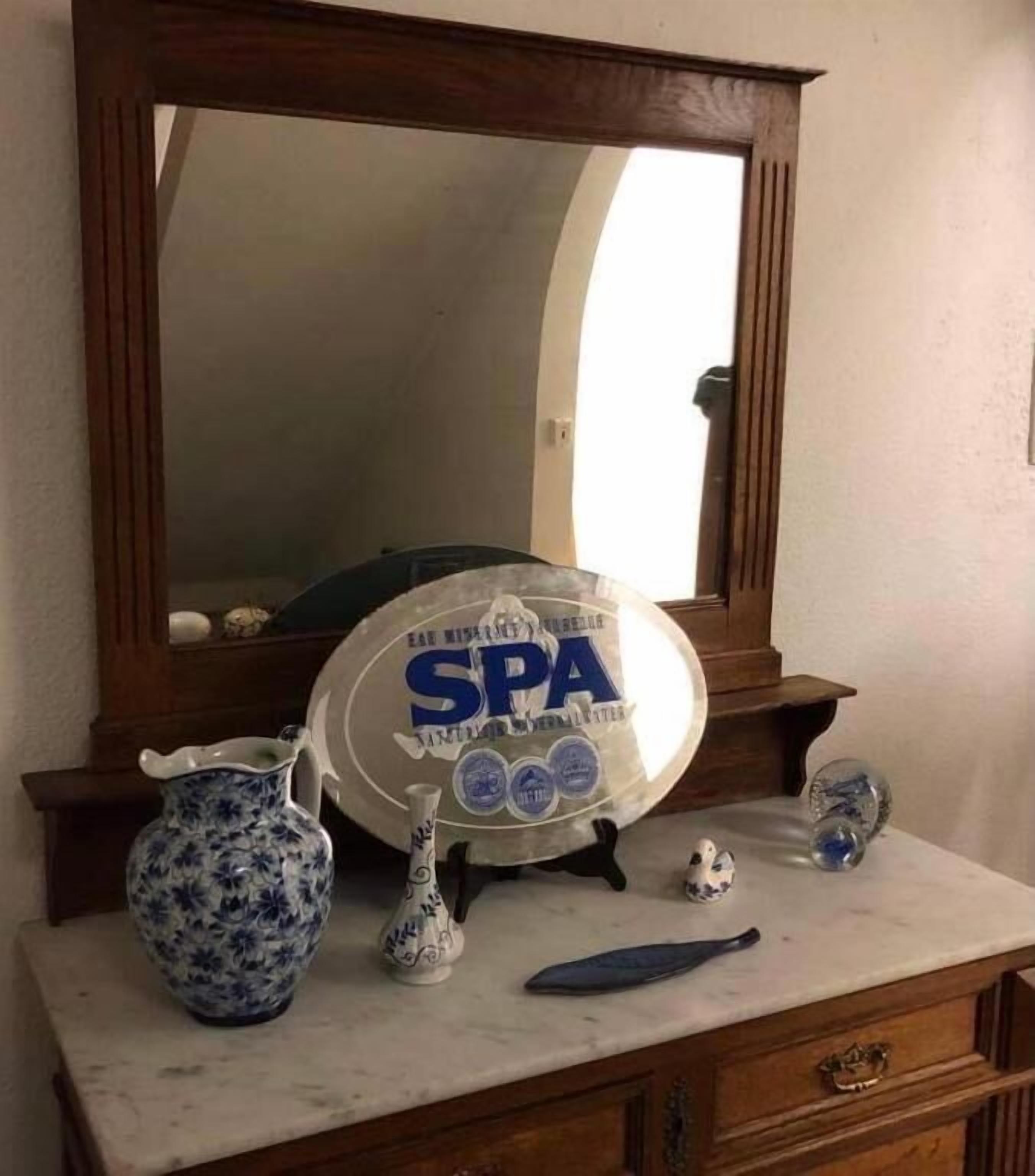 Un meuble-lavabo de salle de bain agrémenté d’un miroir, d’une assiette décorative, d’un pichet et d’un petit vase.