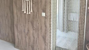 Una habitación con pared de madera, un espejo redondo con flecos y una cortina con cadenas colgantes.