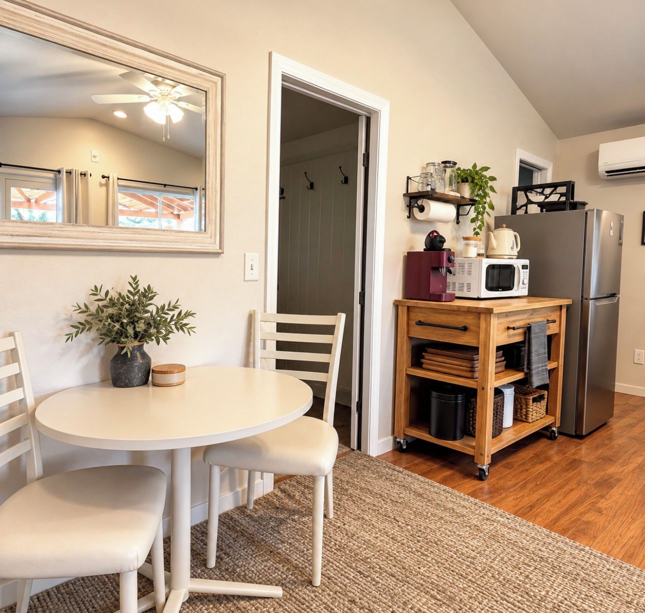 A compact kitchen with a dining area, a ceiling fan, and a refrigerator.