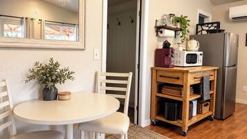 A compact kitchen with a dining area, a ceiling fan, and a refrigerator.