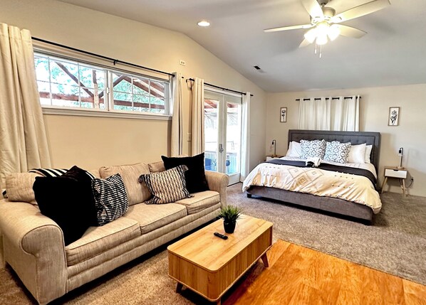 A bedroom with a bed, a sofa, a coffee table, and a nightstand.