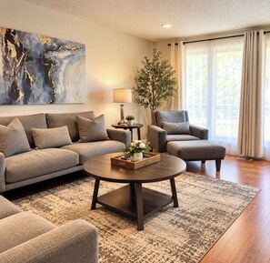 A living room with a sofa, armchair, coffee table, and a painting on the wall. - Family & Dog Friendly-LG Kitchen-Gazebo &Fire Pit- (Medford)