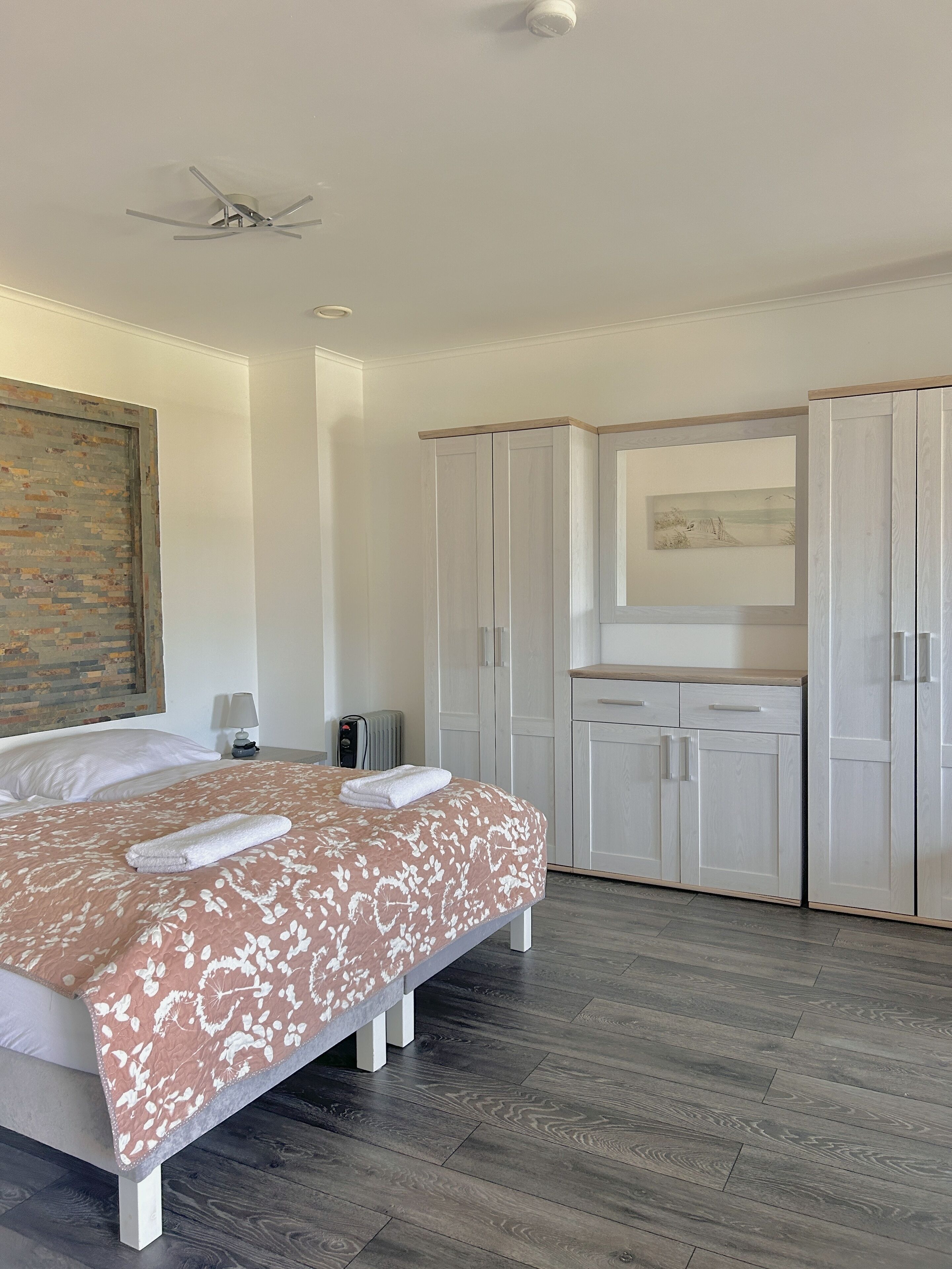 Ein Hotelzimmer mit Bett, Deckenventilator, Kleiderschrank und einem Bild an der Wand.