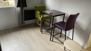 Ein kleiner Raum mit Fenster, Tisch, zwei Stühlen und einer Tür.