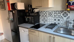 Eine kleine Küche mit Geschirrspüler, Mikrowelle, Kaffeemaschine und Spüle.
