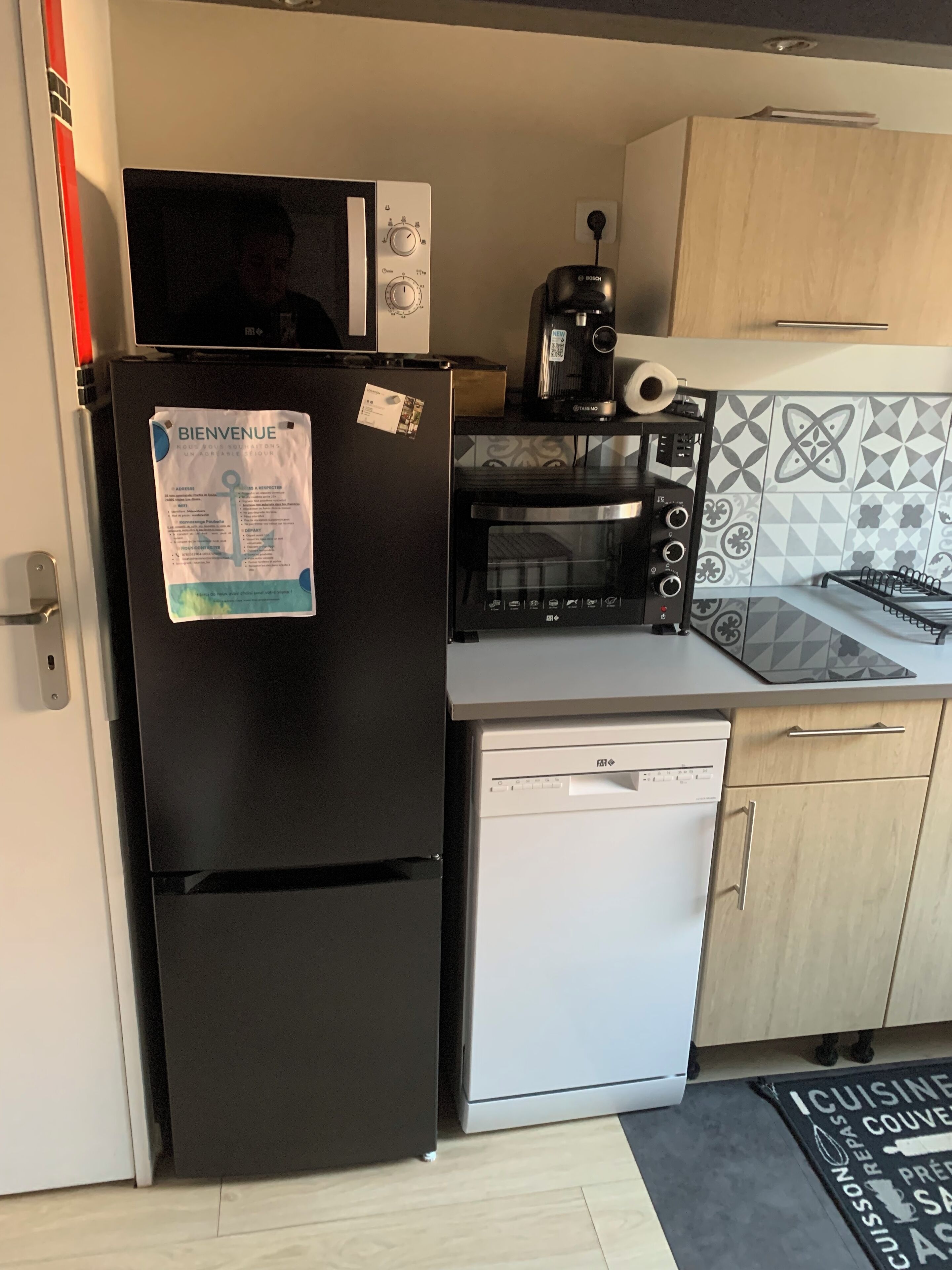 A compact kitchen with a black refrigerator, a microwave, a toaster, and a dishwasher.