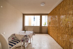 A room with a table and chairs, a window, and a bamboo wall.