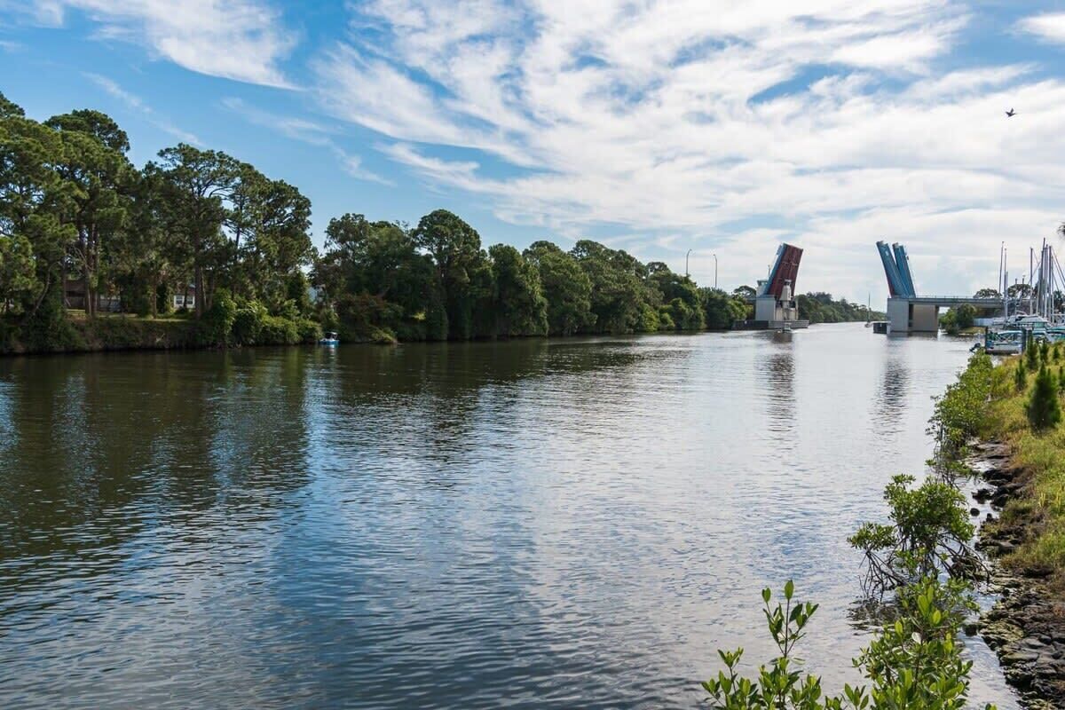 Scenic river view with a drawbridge and lush greenery along the shore