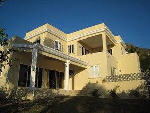 A two-story house with a flat roof, large windows, and a covered front porch.