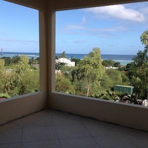 Uma varanda com vista para o mar e vegetação ao redor.