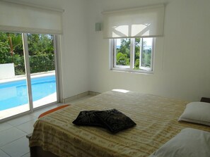A bedroom with a bed, a window, and a view of a swimming pool.