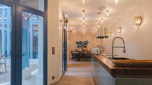 A modern kitchen with a wooden countertop, a sink, and a dining area with a table and chairs. - Villa D'Eaux (Villers-sur-Mer)