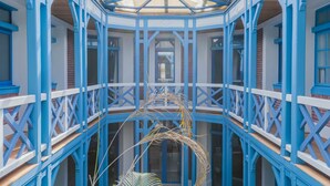 A covered walkway with blue railings and a glass ceiling, connecting multiple levels of a building. - Villa D'Eaux (Villers-sur-Mer)