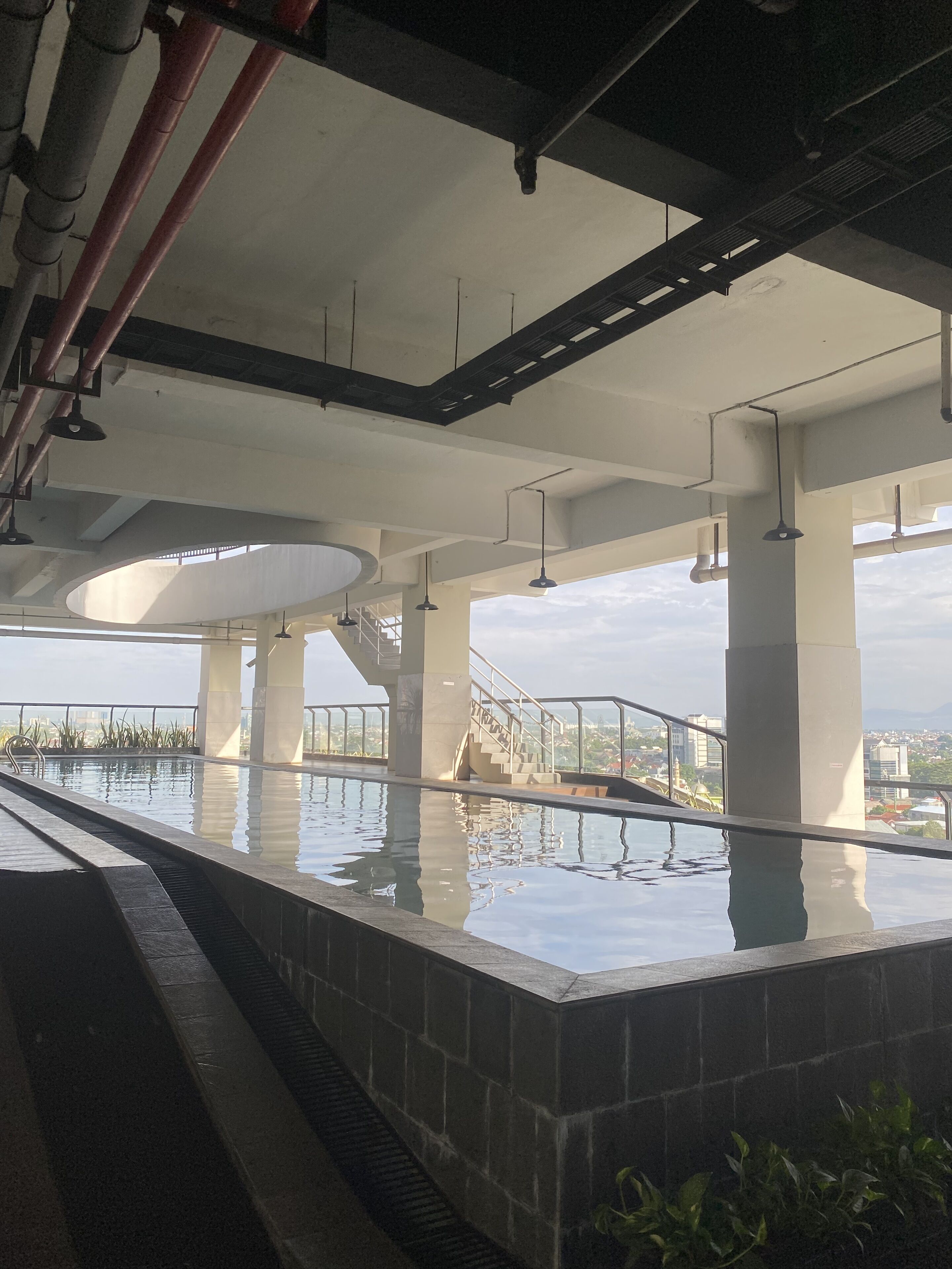 An indoor swimming pool with clear water, surrounded by stone walls and supported by concrete pillars.