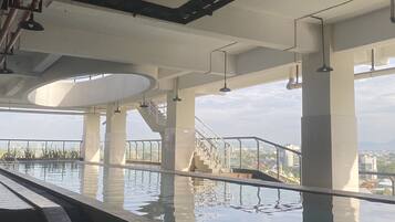 An indoor swimming pool with clear water, surrounded by stone walls and supported by concrete pillars.