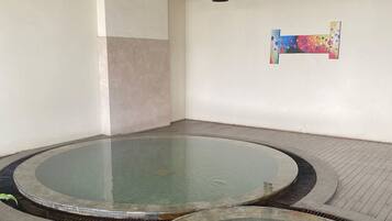 Relax in a serene spa area featuring two hot tubs surrounded by a tiled floor and ceiling fan.