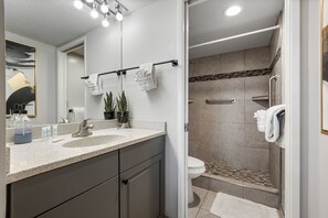 Un baño moderno con lavamanos, espejo y zona de ducha.
