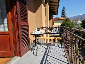 Un balcón con una mesa preparada para tomar té, una puerta de madera y vistas del entorno.